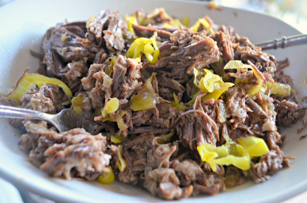 Italian Beef Roast shredded in bowl with pepperoncini peppers