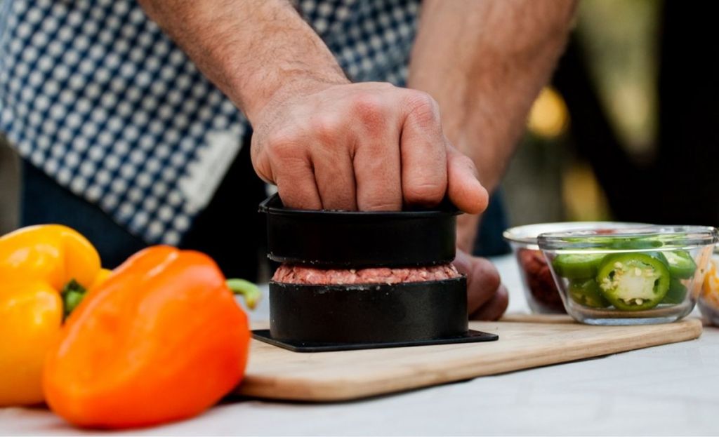 A person using a burger press outside 