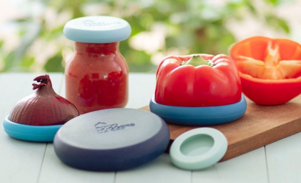 A red pepper and an onion with food huggers covering them on a table