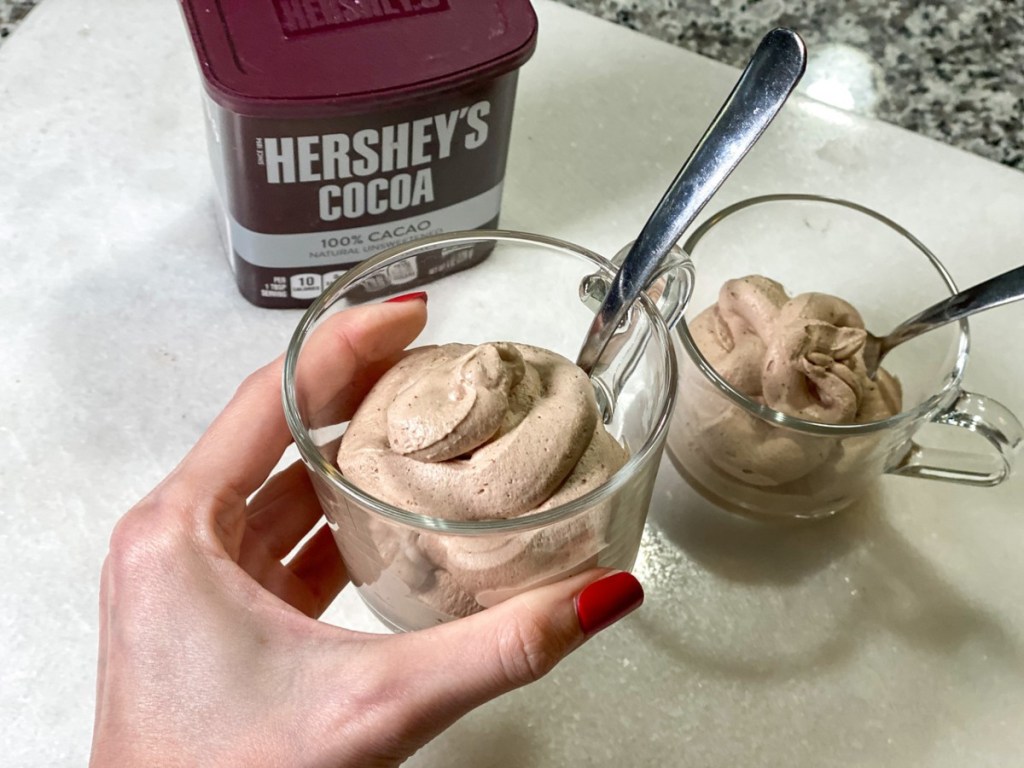 hand holding homemade frosty in glass mug with spoon