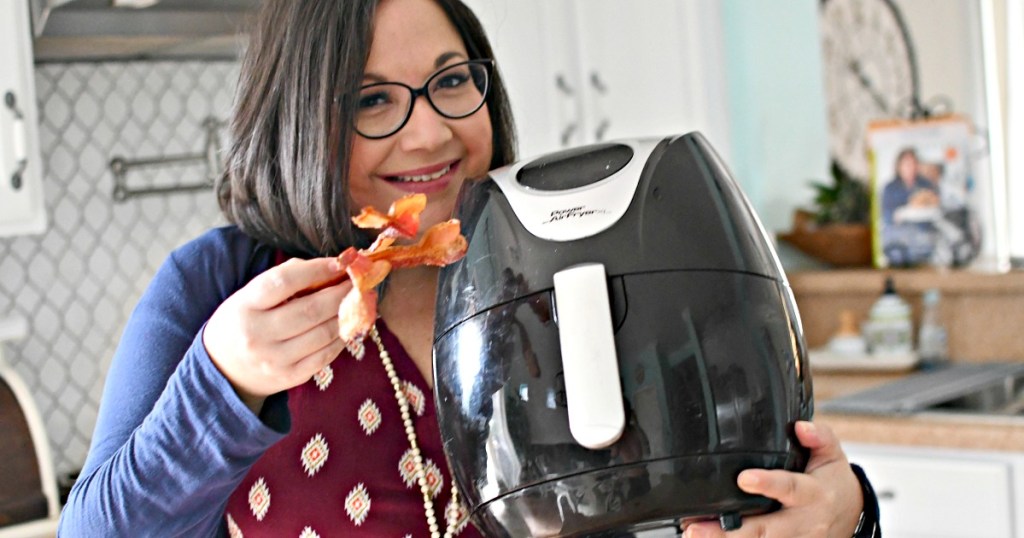 woman holding power xl air fryer and bacon