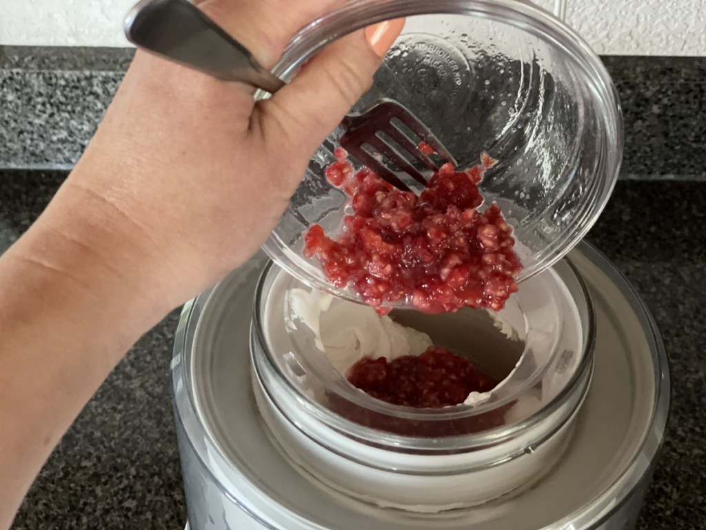 adding raspberries to keto ice cream in ice cream maker