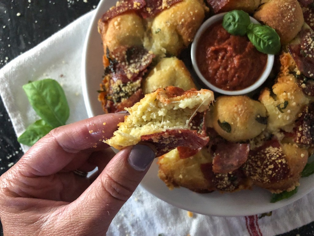 Hand holding a piece of pull-apart keto pizza