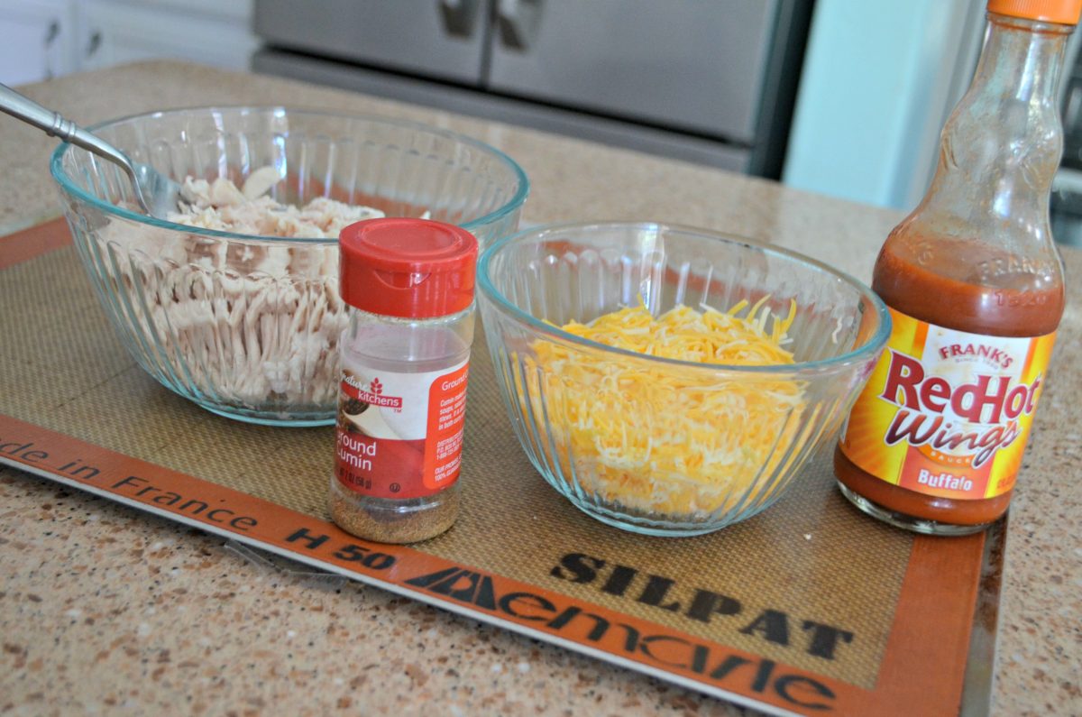 the ingredients for taquitos including cumin, chicken, buffalo sauce, and cheese