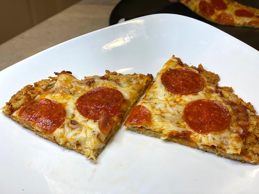 two slices of keto chicken pizza crust with pepperonis on plate