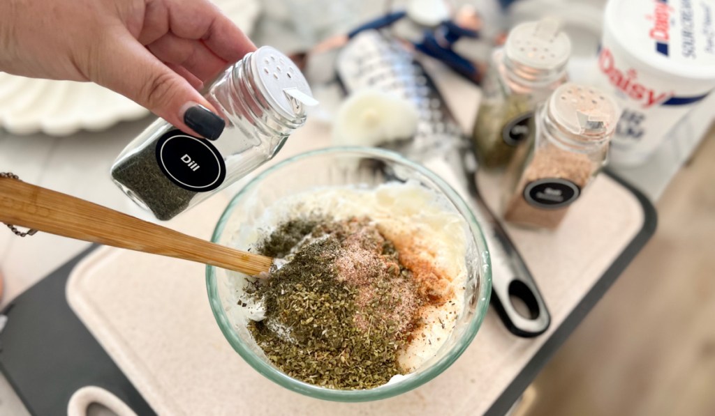 adding dried dill to keto dill dip in a bowl