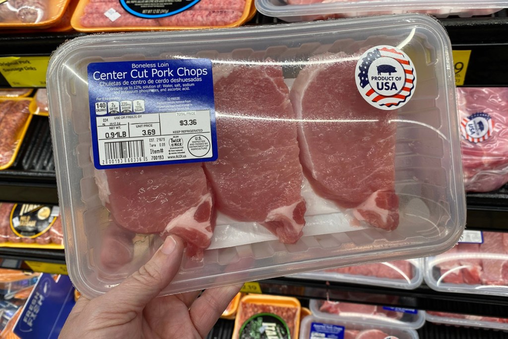 hand holding a pack of pork chops at aldi