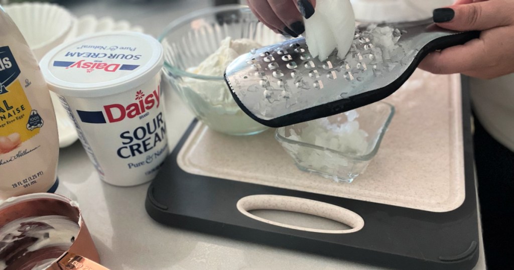 shredding onion over a bowl