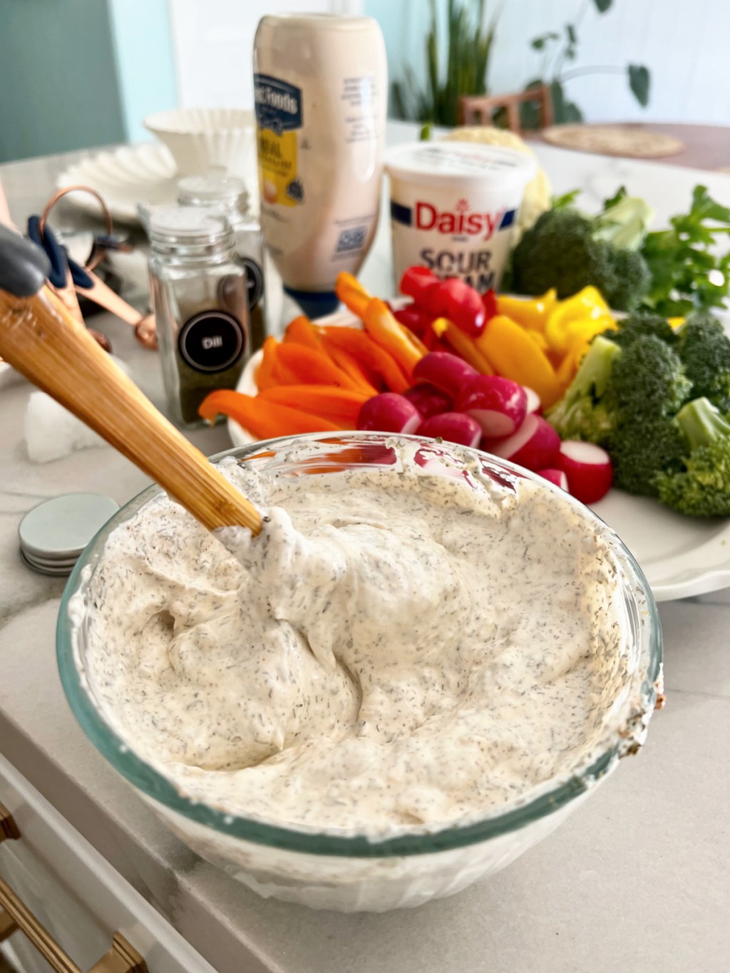 stirring keto dill dip in a glass bowl