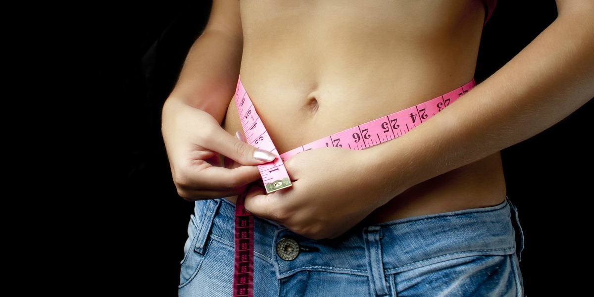 mct oil benefits — woman with tape measure around waist showing weight loss