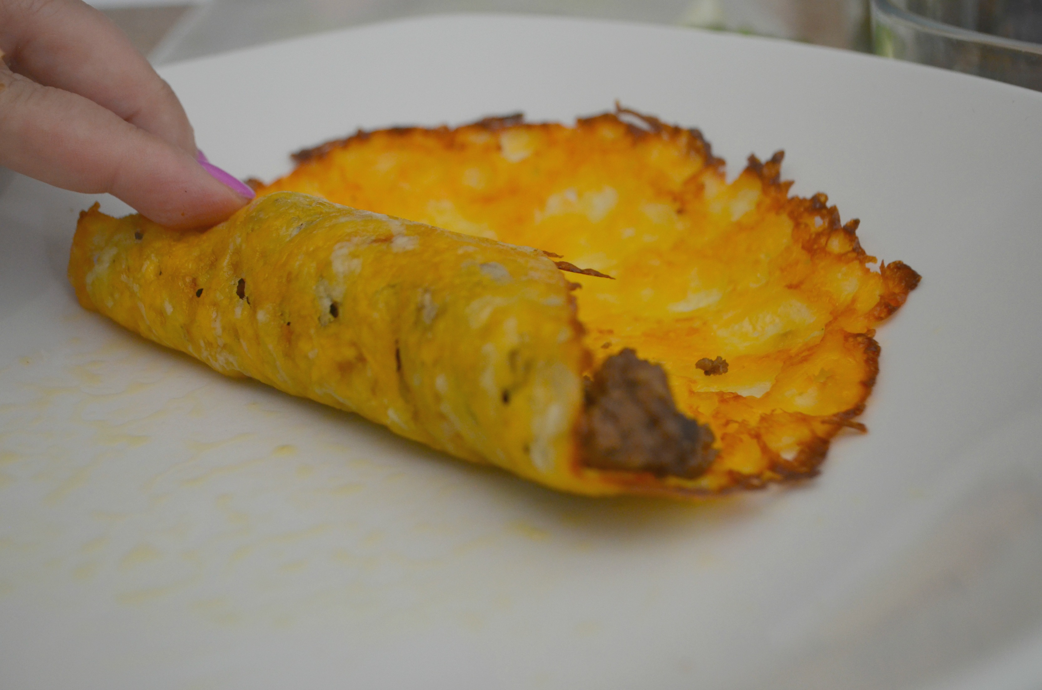 Rolling up the ground beef keto enchiladas in cheese shells