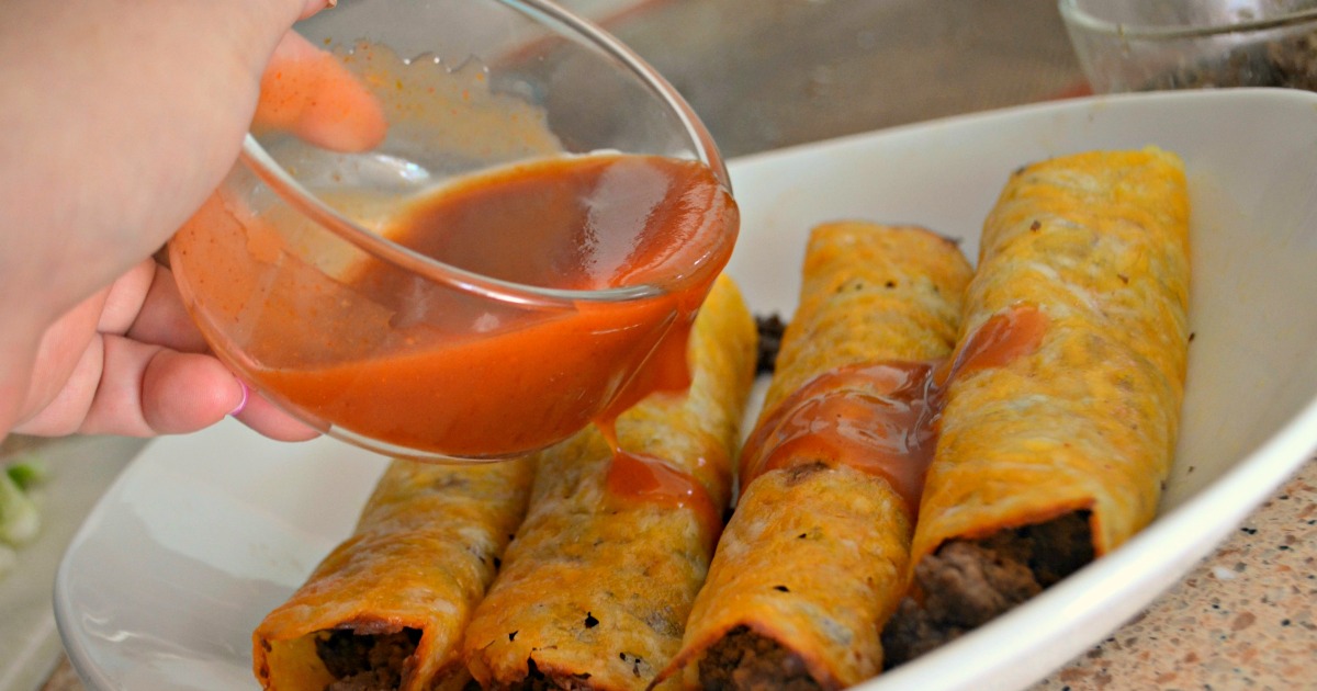 Pouring sauce over the plated keto ground beef enchiladas