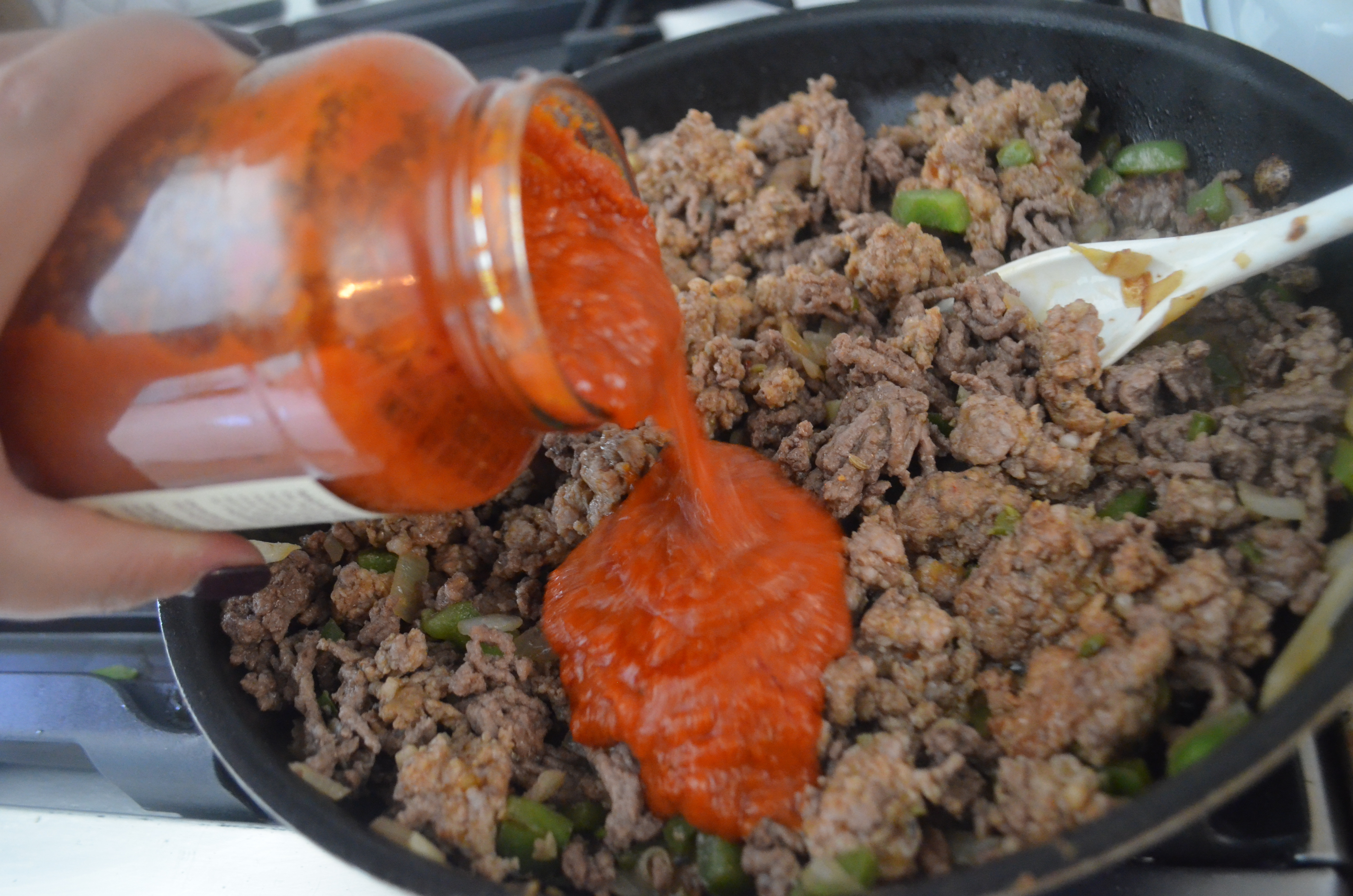 raos low carb homemade marinara sauce - pouring sauce into ground beef