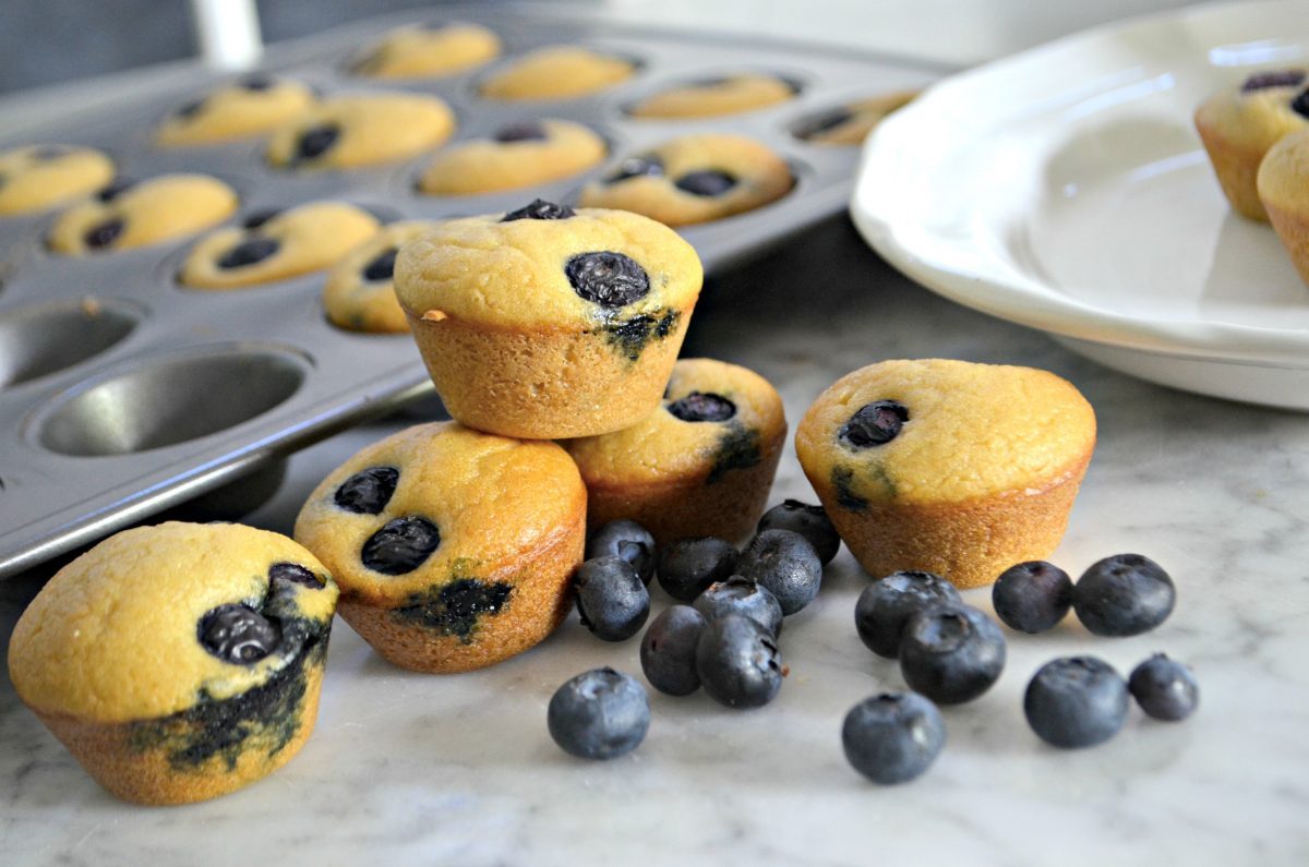 Keto Mini Blueberry Pancake Bites - cooked mini muffins stacked next to blueberries