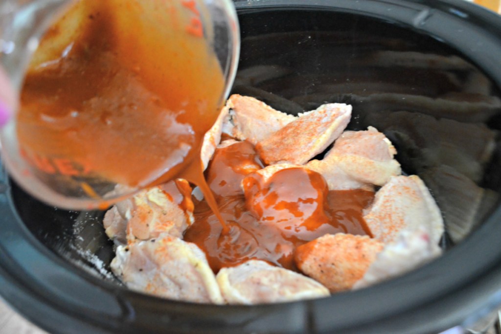 pouring sauce onto wings