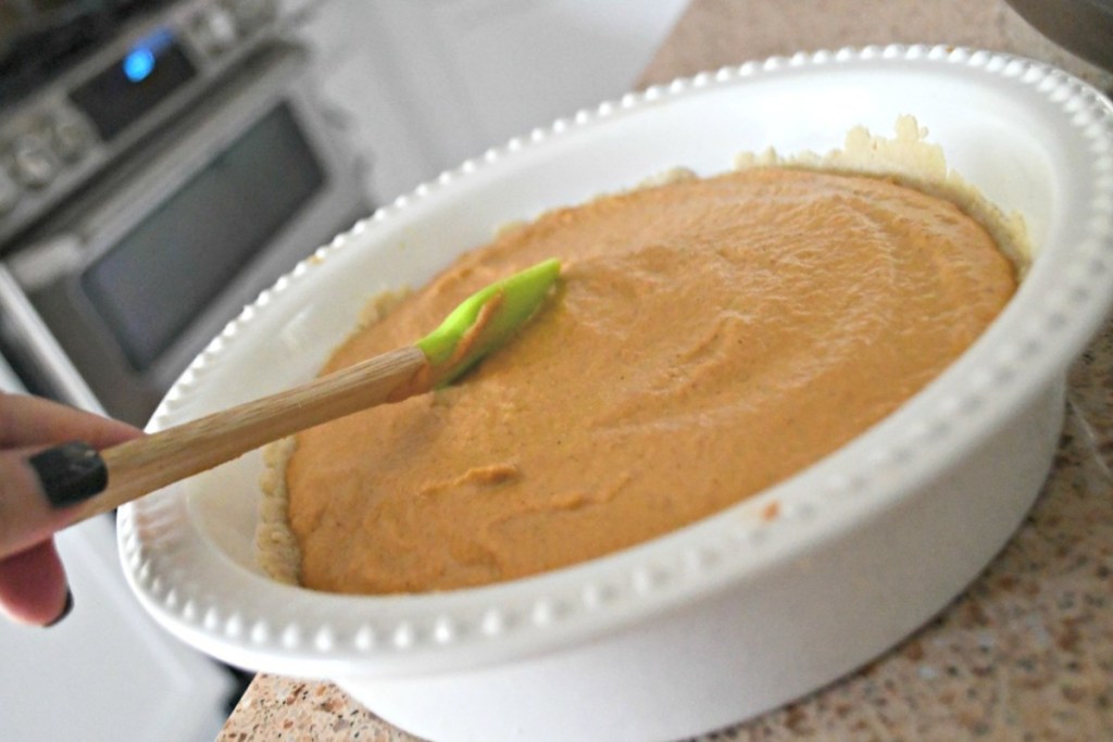 smoothing out pumpkin pie filling with spatula