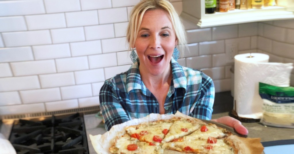 woman holding keto pizza with tomatoes 