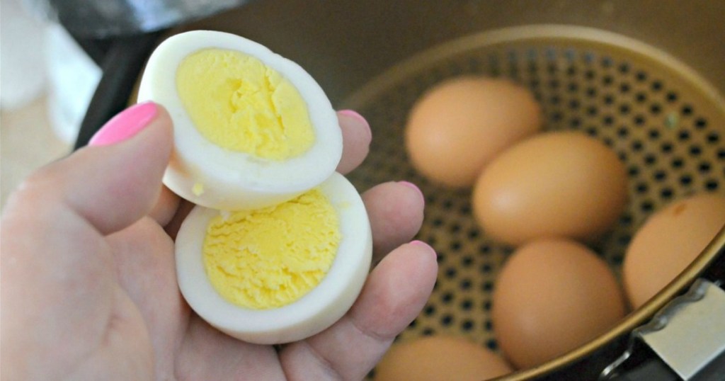 hand holding hardboiled eggs next to air fryer