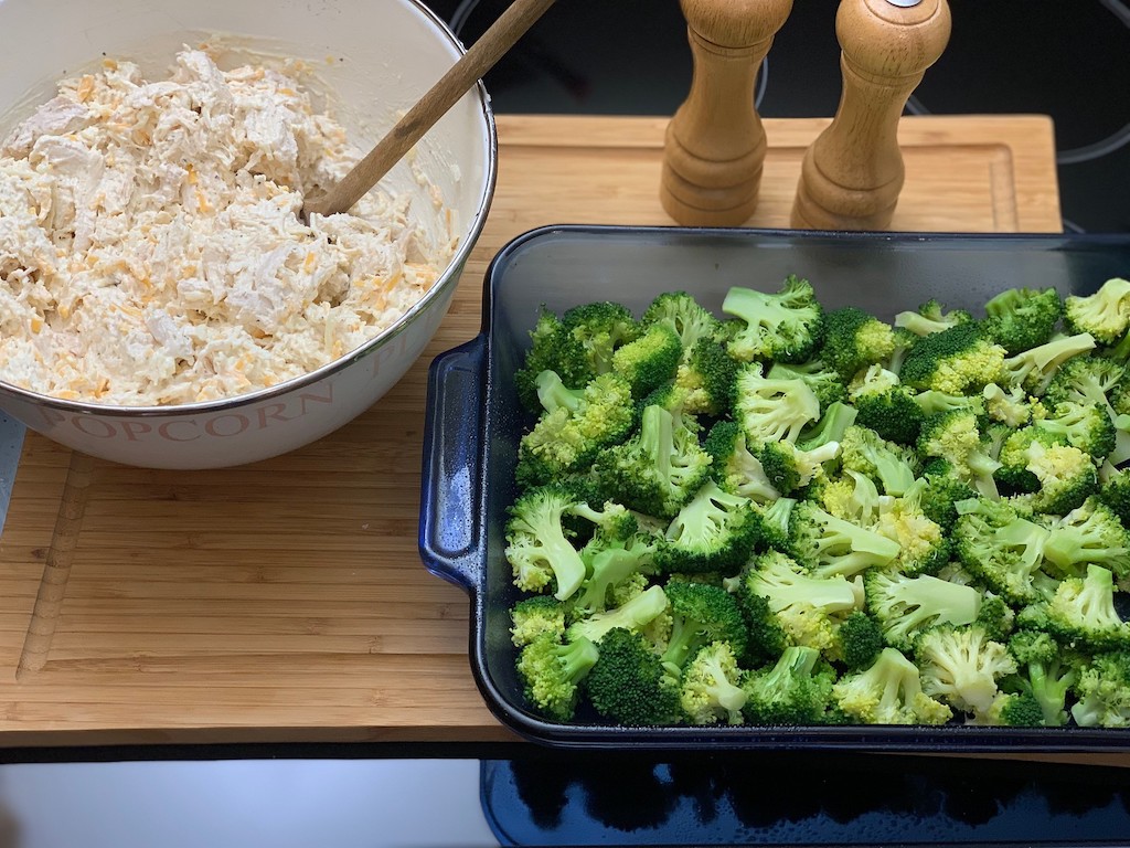 bowl of shredded chicken mixture and broccoli with casserole dish 