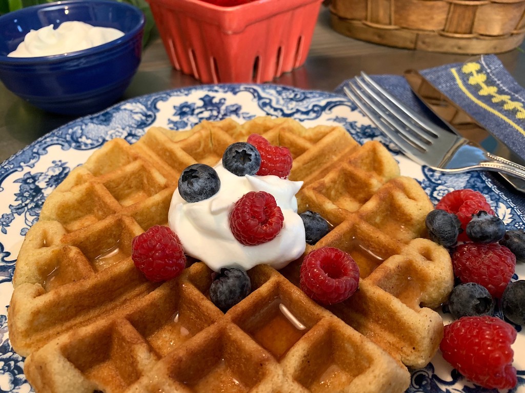 keto waffle on a plate with berries and whipped cream 