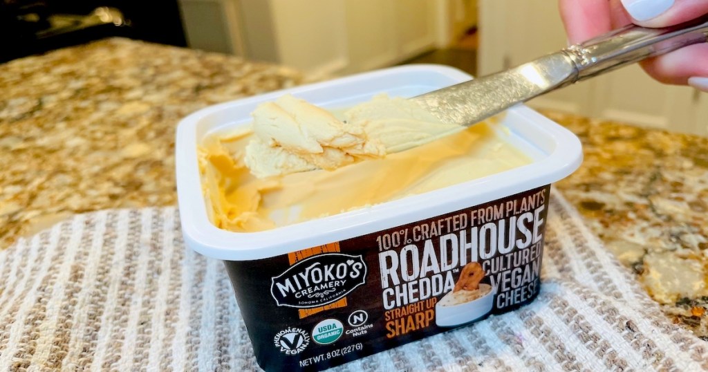 hand holding knife with miyokos cheese spread on it