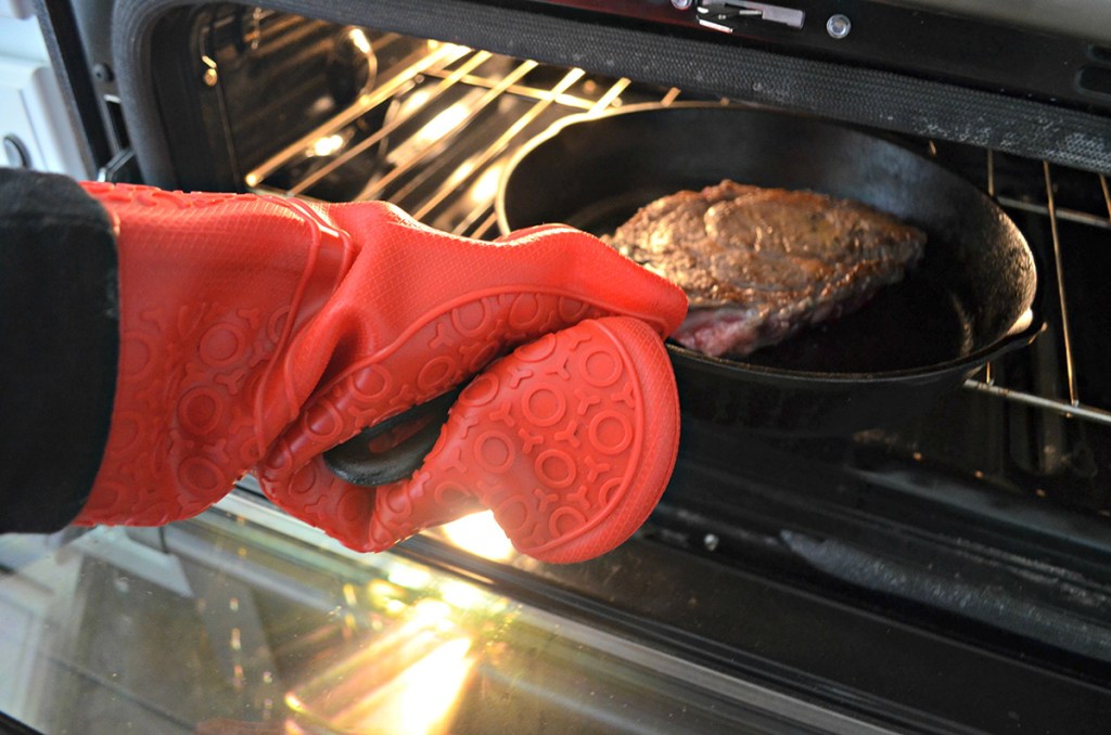 pulling cast iron pan with ribeye from oven