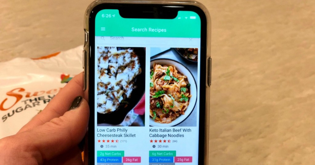 A hand holding a phone with the Carb Manager App open