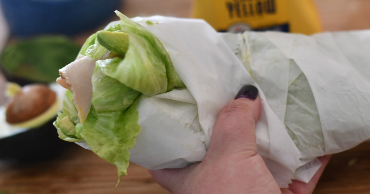 holding homemade lettuce wrapped sandwich 