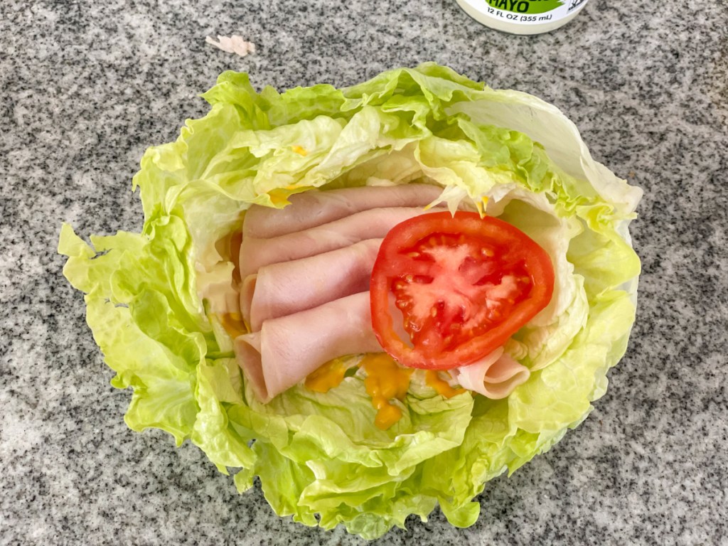 iceberg lettuce bowl with mayo, mustard, turkey lunch meat, and tomato