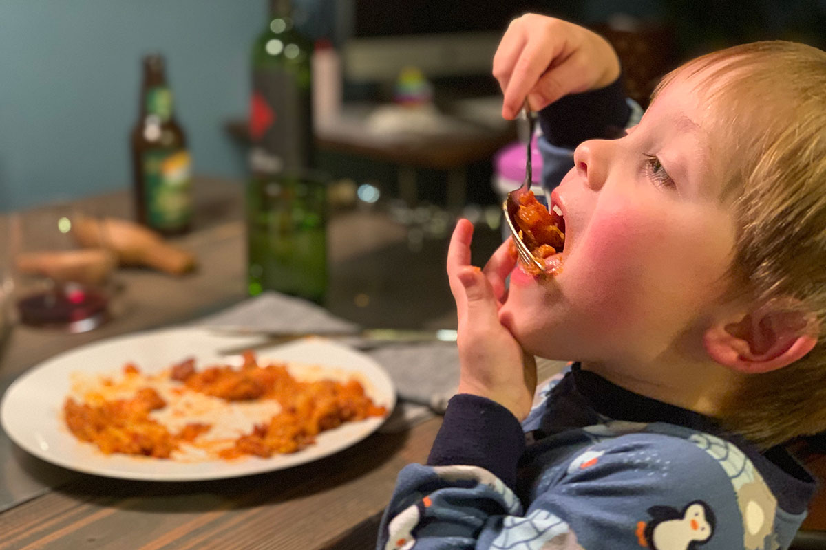 Keto Italian Sausage and Spaghetti Squash Casserole - young boy eating a large bit of Italian squash casserole