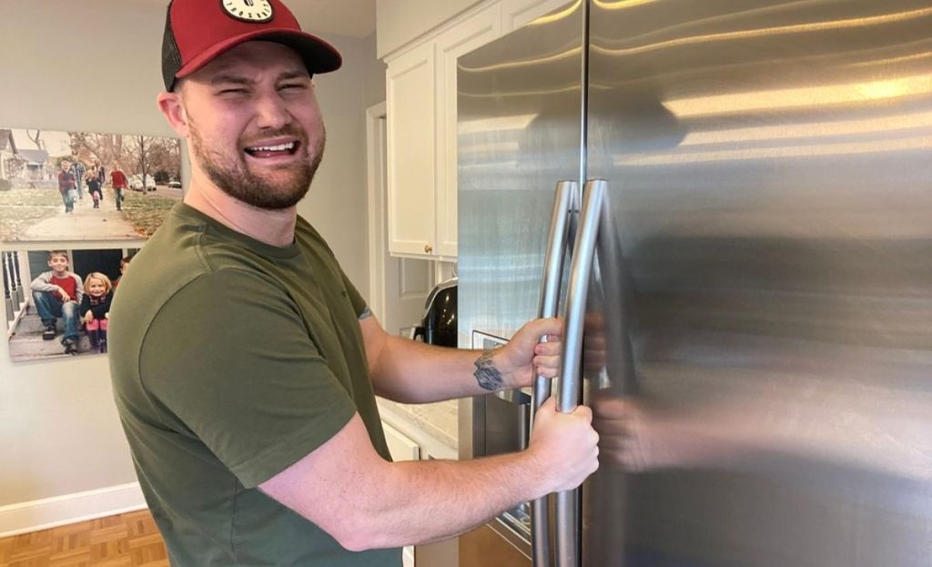 A man with a sad face opening fridge doors