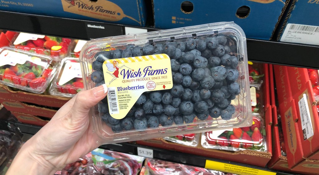 holding pack of blueberries fruits in produce section