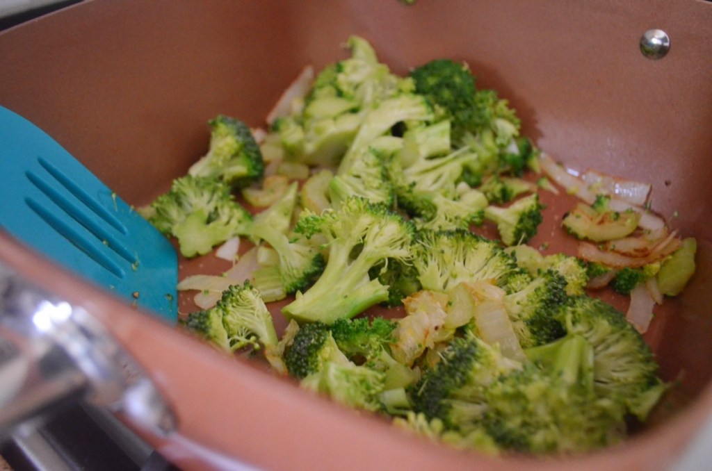 cooking broccoli in pan with onions