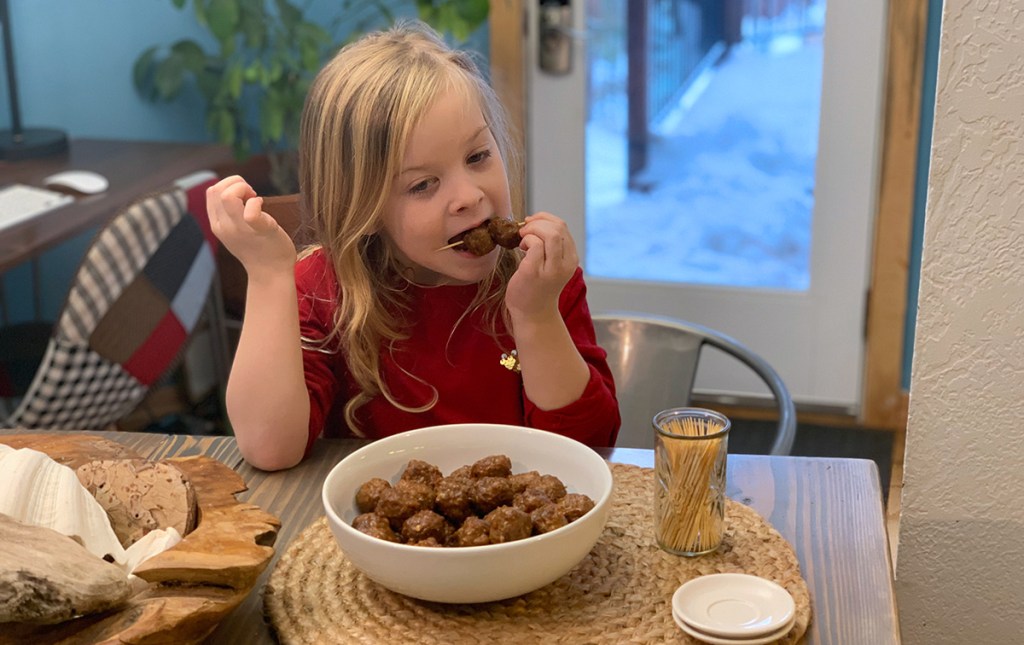 young girl eating meatballs