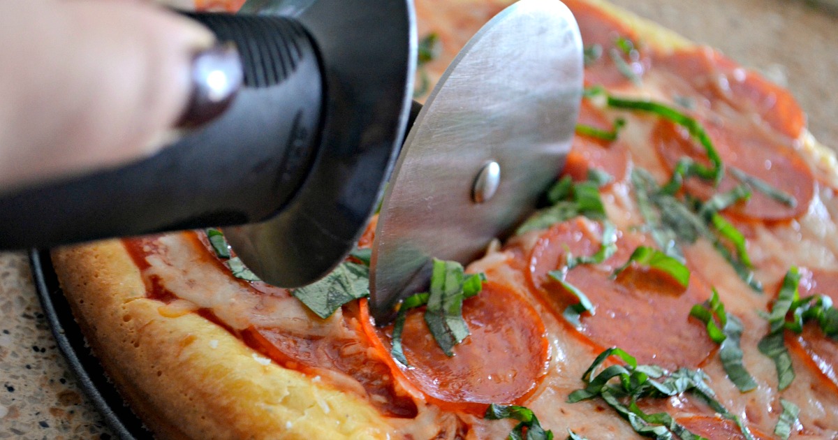 pizza cutter slicing up keto pepperoni pizza