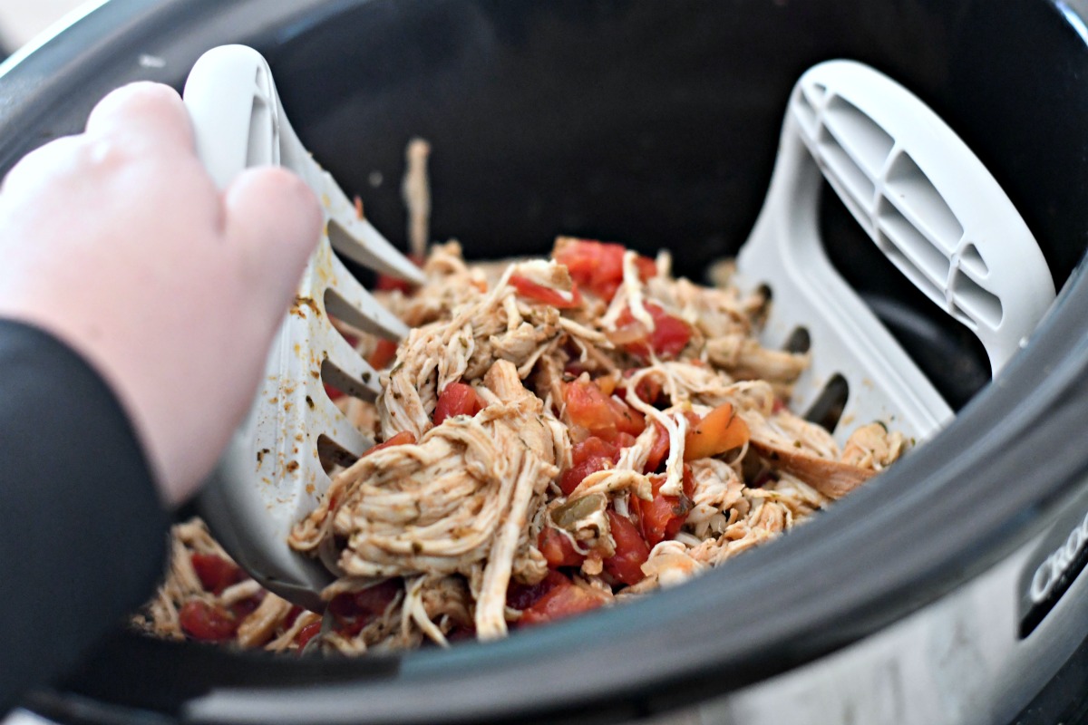 closeup of the keto slow cooker shredded chicken tacos being shredded in the crock pot