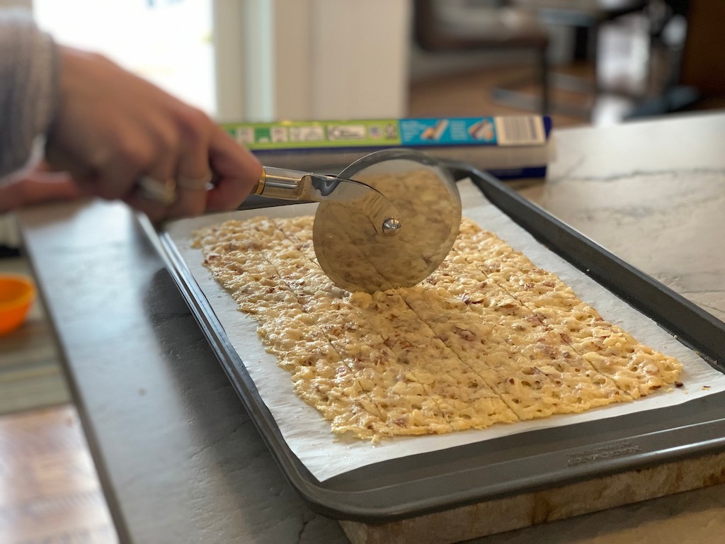 using pizza slicer to slice keto low carb crackers on pan 