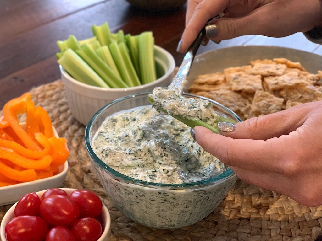 putting spinach dip on celery stick