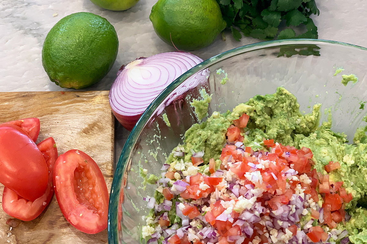 mixing together the guacamole ingredients in a bowl