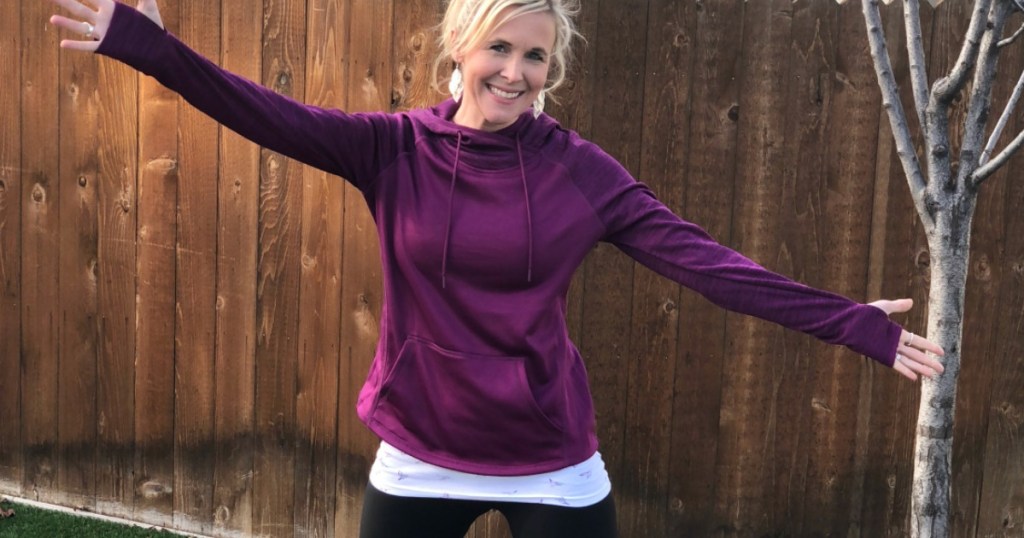 woman with arms open in purple sweatshirt 