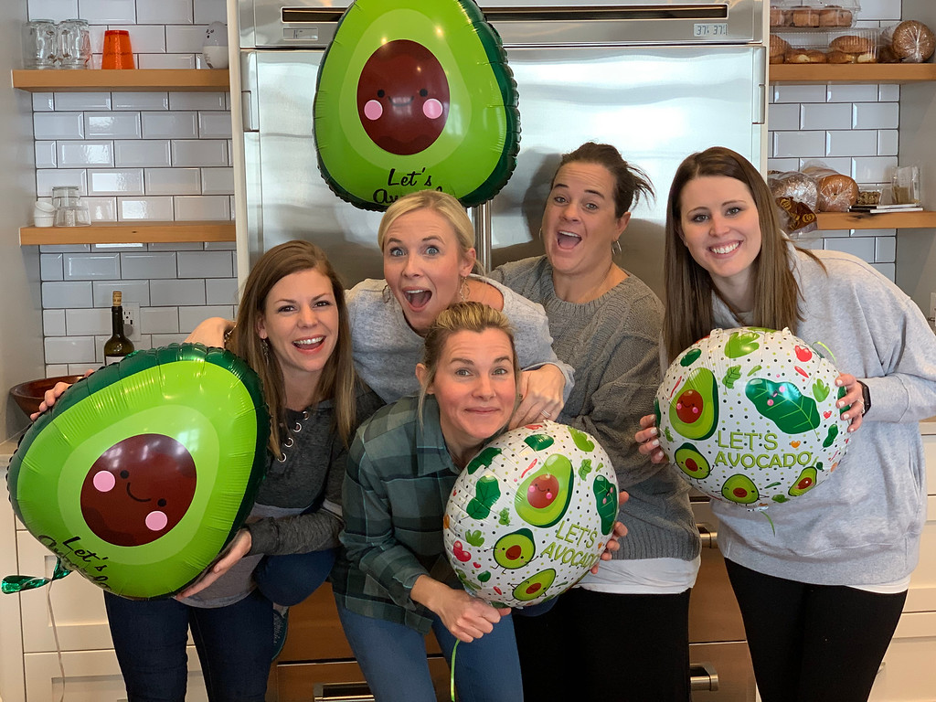 Women standing in front of a fridge holding balloons