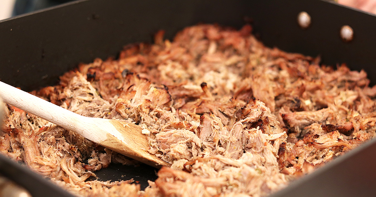 A roasting pan loaded with crispy broiled shredded pork