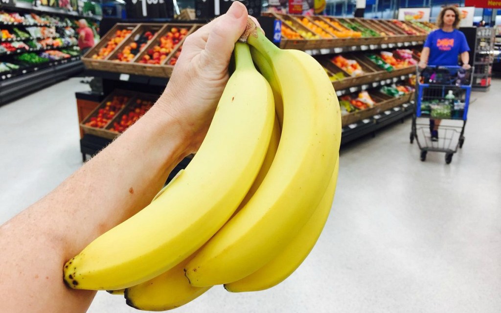 holding up bunch of yellow bananas