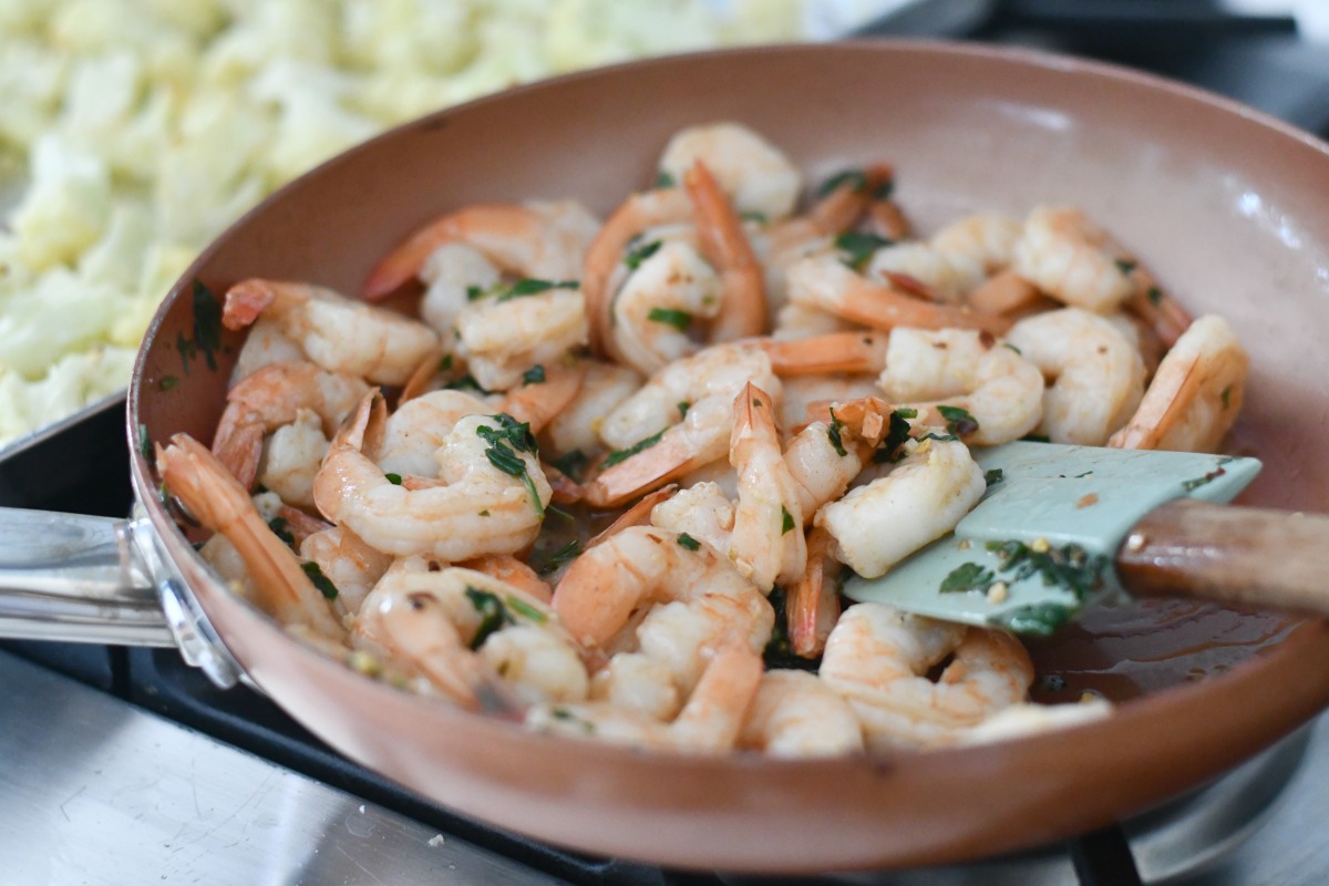 mixing herbs with shrimp in the pan