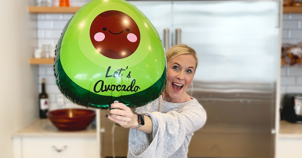 woman holding up avocado shaped balloon