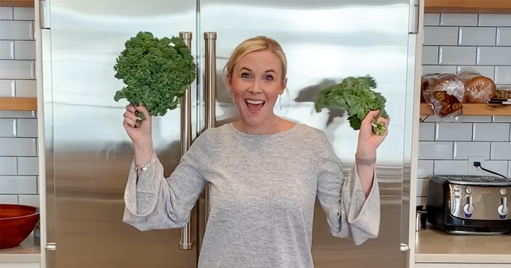 woman holding up kale leaves in kitchen