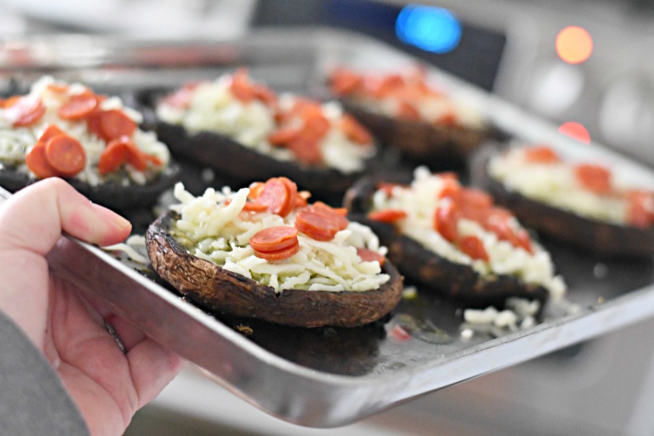 holding up a pan of unbaked portobello mushroom pesto pizzas