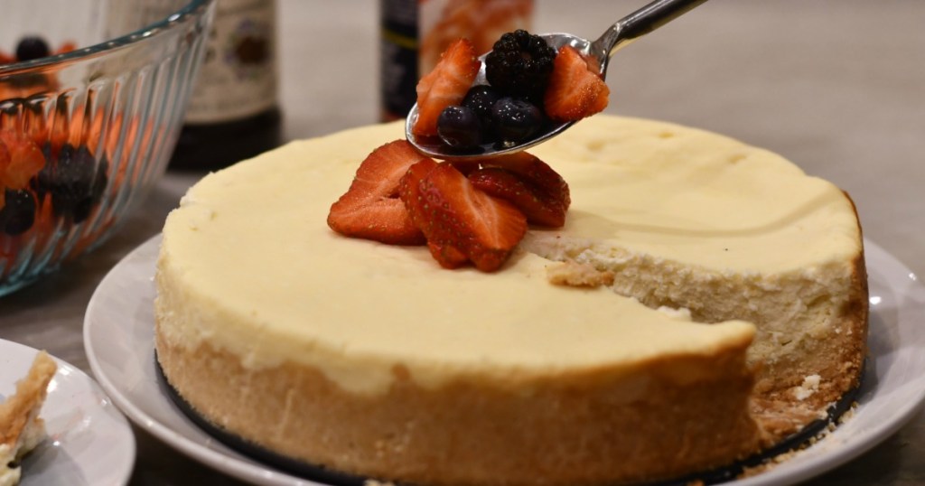 putting berries on keto cheesecake on a plate