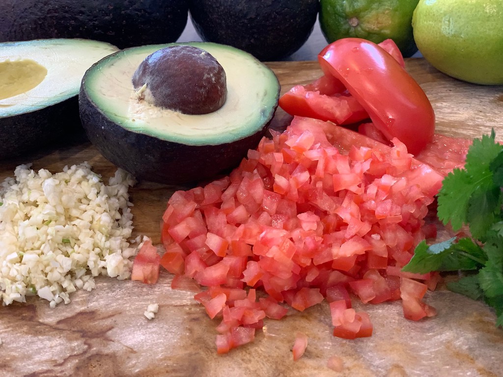 avocado, diced tomatoes and minced garlic on cutting board