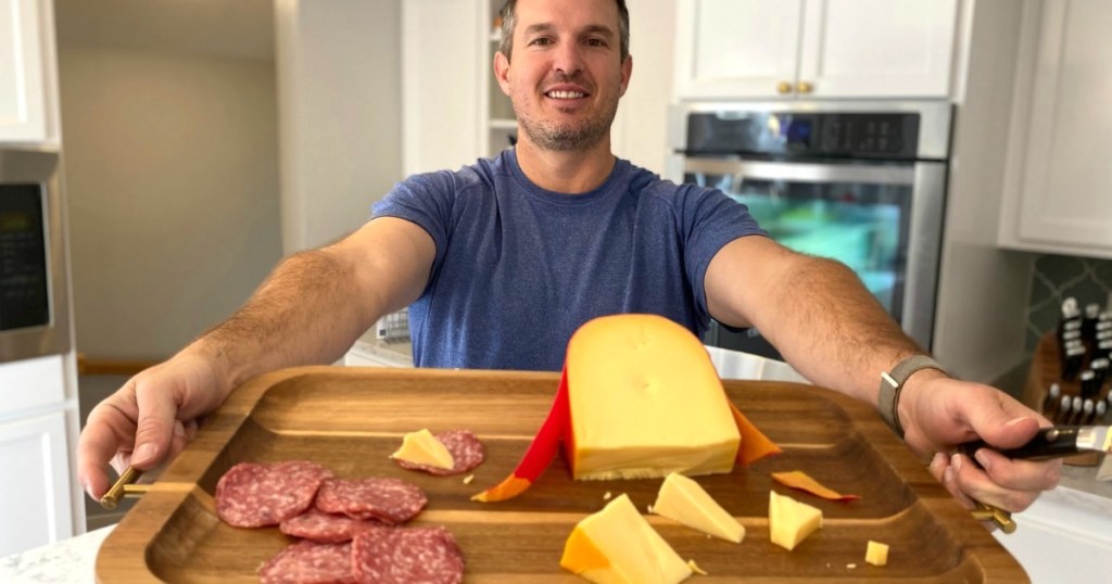 man holding tray with meat and cheese 
